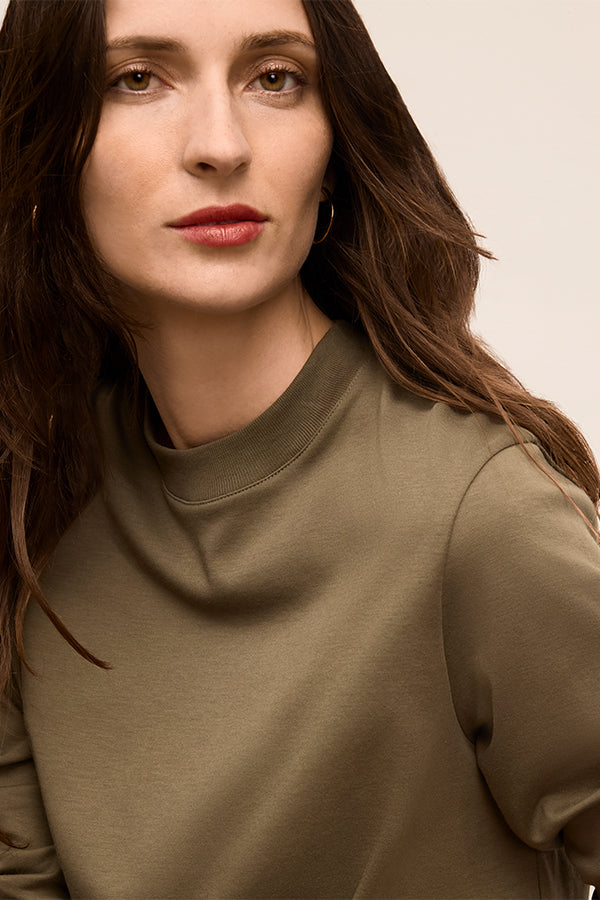 Woman wearing a green sweater against a neutral background | Exclude