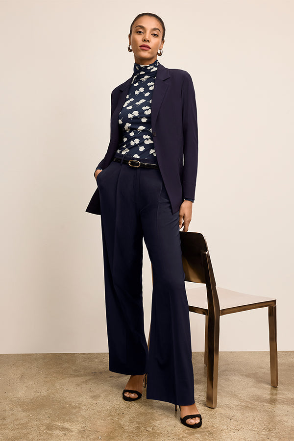 Woman wearing a navy suit with a floral blouse against a beige background | Exclude | Grid