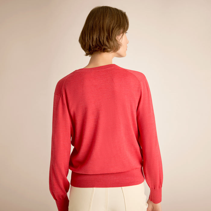 Person wearing a red sweater against a beige background
