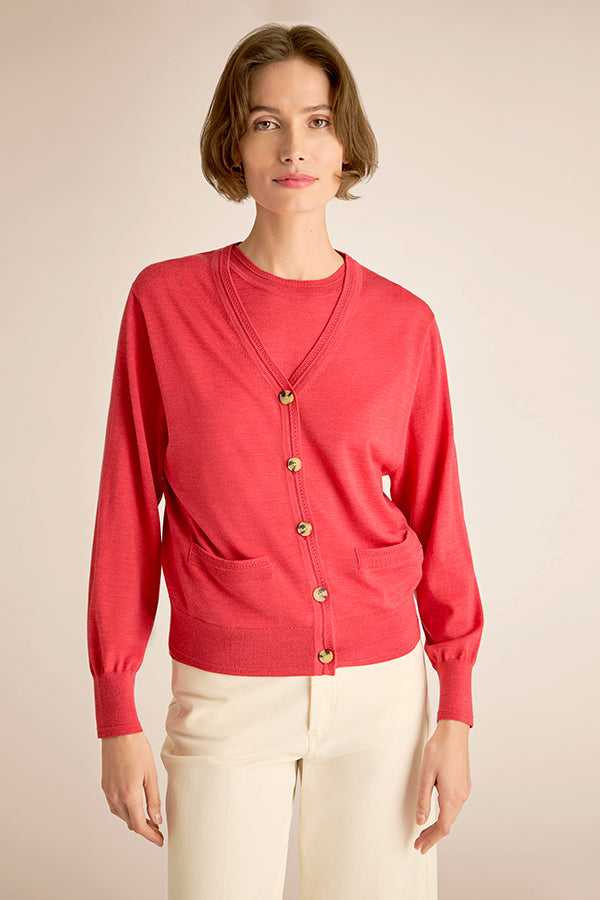 Woman wearing a red cardigan with gold buttons on a beige background | Exclude | Grid