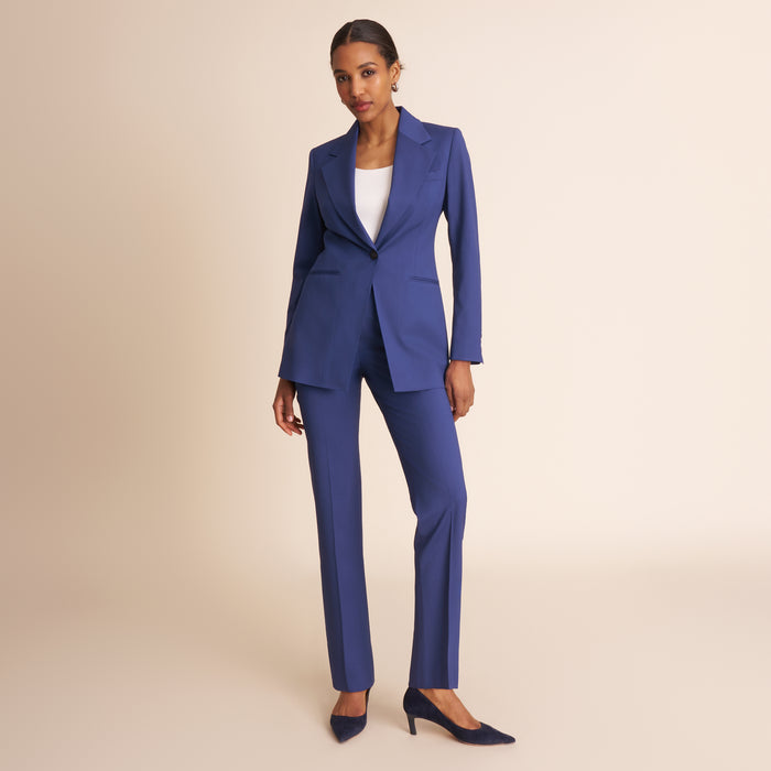 Woman wearing a blue suit with a white top on a beige background