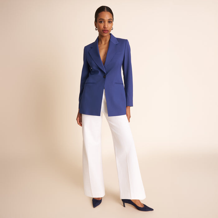 Woman wearing a blue suit with a white top on a beige background