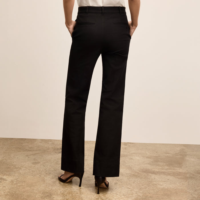 Person wearing black pants on a beige background