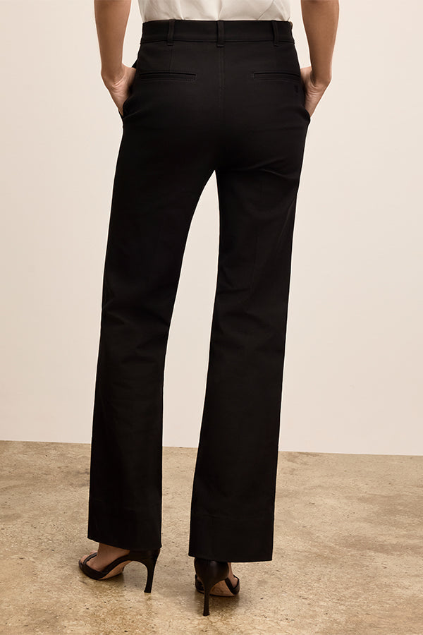 Person wearing black pants standing against a plain background | Exclude