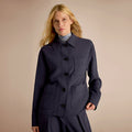 Woman wearing a navy blue coat with a beige background | Lead