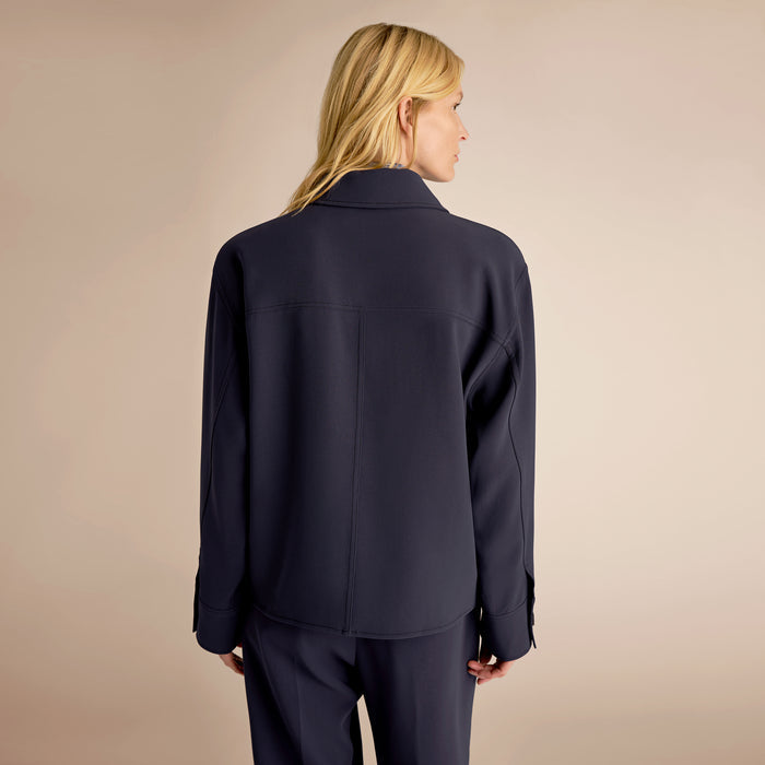 Person wearing a navy suit on a beige background