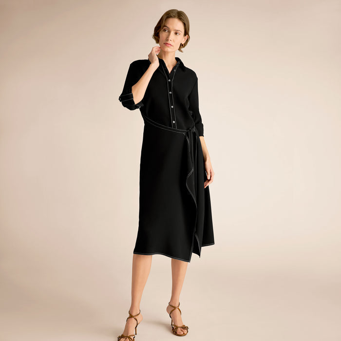 Woman wearing a black dress with a belt on a beige background | Lead