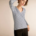 Woman wearing a blue and white patterned long-sleeve top against a beige background | Lead