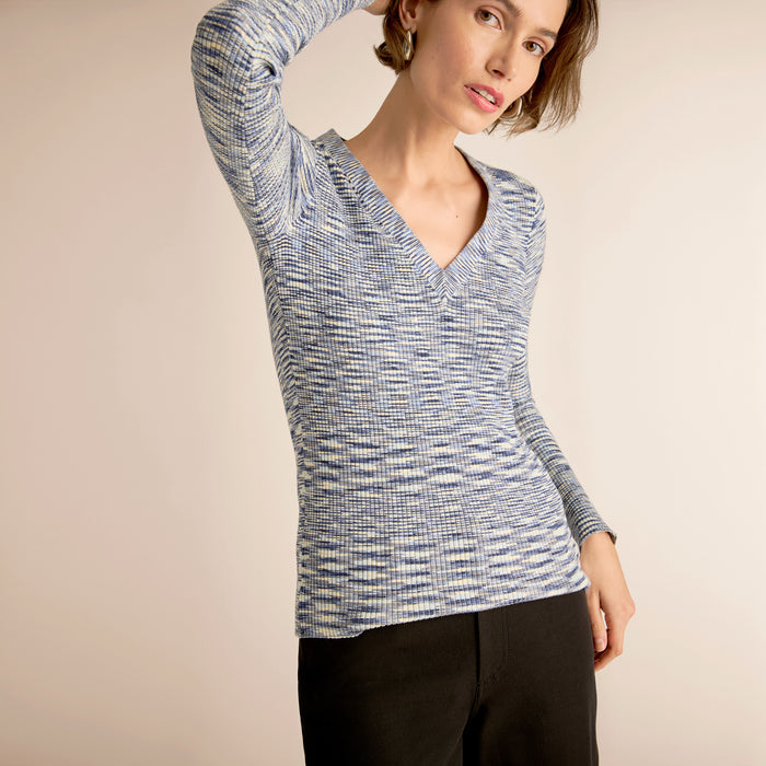 Woman wearing a blue and white patterned long-sleeve top against a beige background | Lead