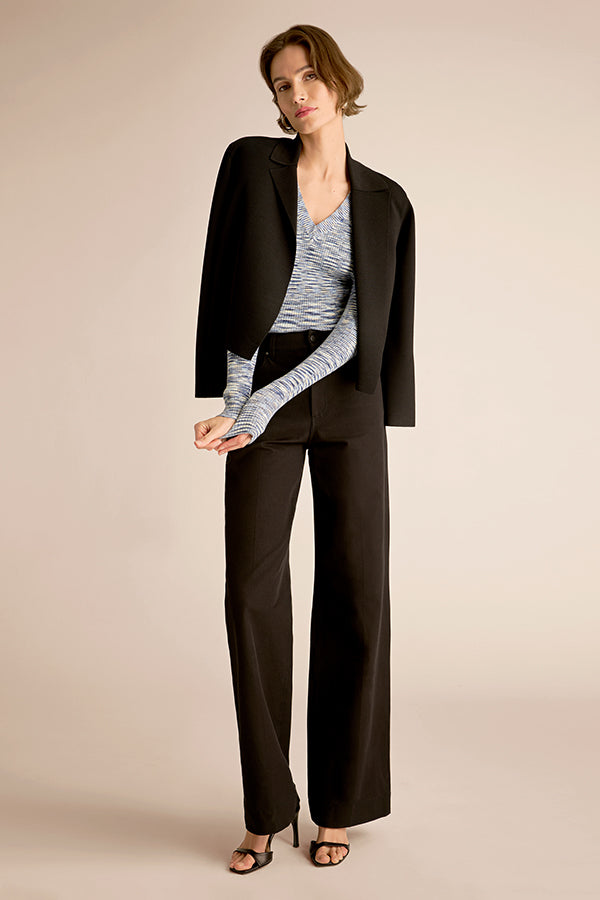 Woman wearing a black suit with a gray top on a beige background | Exclude