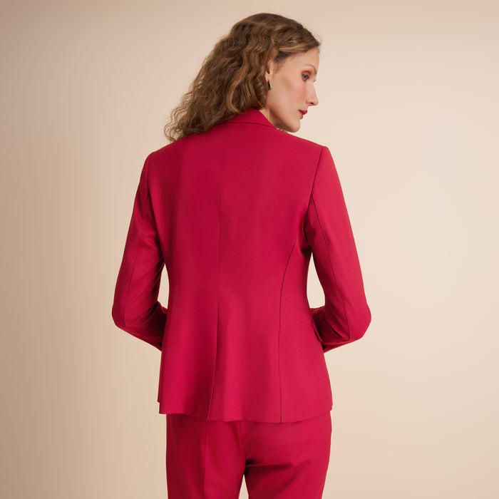 Woman wearing a red suit against a beige background