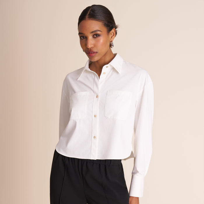 Woman wearing a white shirt and black pants against a beige background | Lead