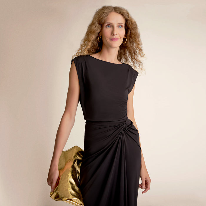 Woman wearing a black dress holding a gold clutch