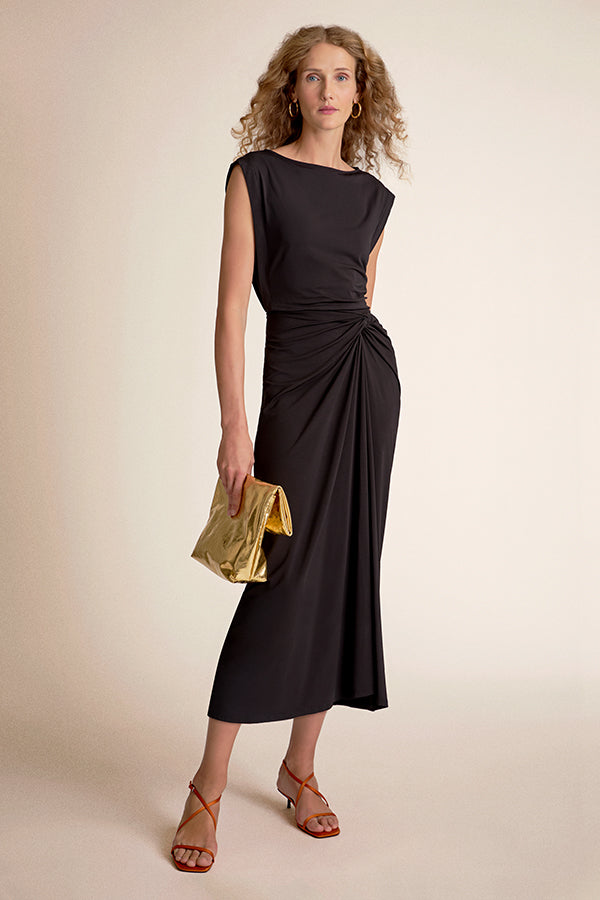 Woman wearing a black dress holding a gold clutch | Grid | Exclude