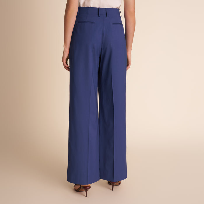 Blue wide-leg pants worn by a person on a beige background.