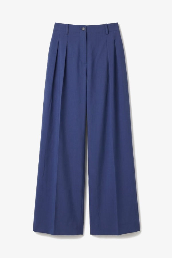 Blue pleated pants on a light gray background. | Still | Exclude