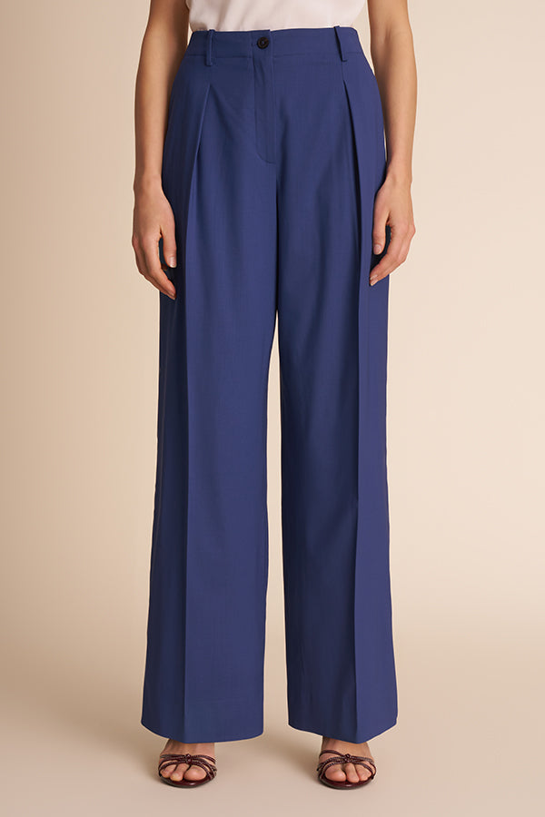 Blue pants worn by a person on a beige background.  | Exclude | Grid